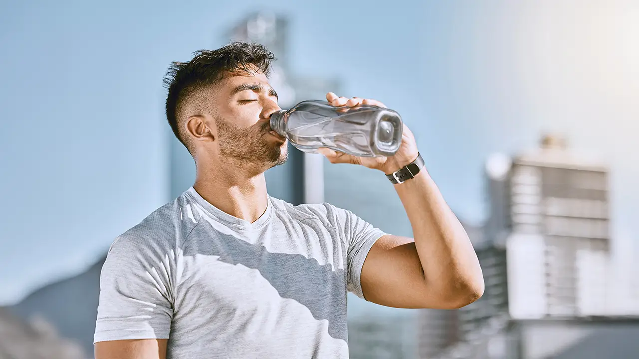 Winter Wellness Guide: Smart Ways To Boost Immune System Naturally Man drinking water outdoors to stay hydrated and support immune system health during warm weather.
